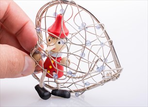 Wooden Pinocchio doll sitting in a heart shaped cage