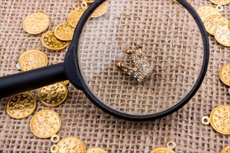 Crown under magnifying glass with fake gold coins