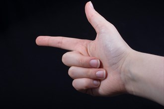 Hand gesture pointing fingers pistol-like handgun on black