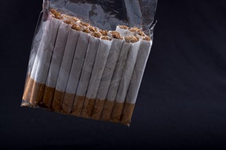 Pack of cigarette hanging on black background