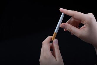 Hand is breaking a cigarette on a black background