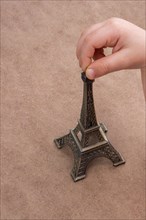Child holding the little model of Eiffel Tower in hand