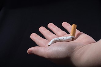 Hand is breaking a cigarette on a black background