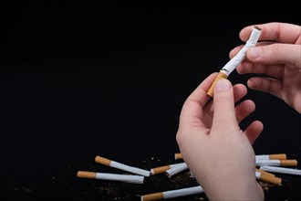 Hand is breaking a cigarette on a black background