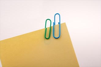 Hand holding a notepaper with paper clips on a white background