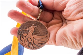 Hand holding a medal with blue and yellow ribbon