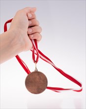 Hand holding a medal with red and white ribbon