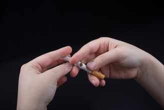 Hand is breaking a cigarette on a black background
