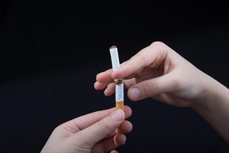 Hand is breaking a cigarette on a black background