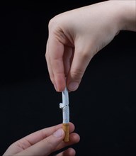 Hand is breaking a cigarette on a black background