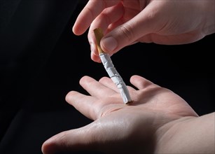 Hand is breaking a cigarette on a black background