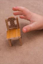 Child holding a wooden toy chair on brown background