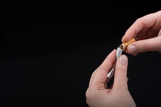 Hand is breaking a cigarette on a black background
