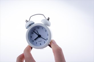 Alarm clock in hand on a white background