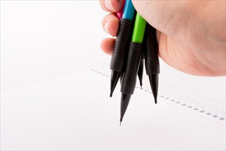 Mechanical pencils of various color in hand on white background