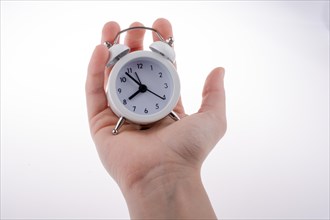 Alarm clock in hand on a white background