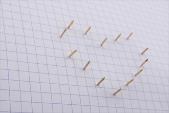 Nails make hole on paper forming a heart shape