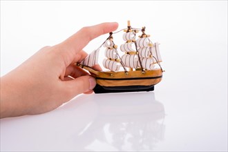 Hand in touch with a little model sailboat on a white background