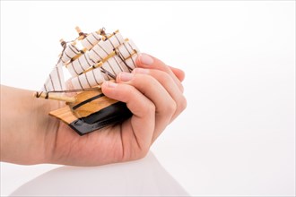 Hand holding a Little model sailboat on a white background