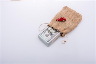 Toy car and bundle of US dollar in a sack on a white background