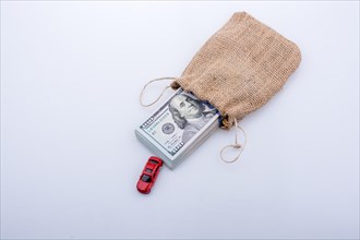 Toy car and bundle of US dollar in a sack on a white background
