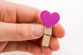 Hand holding a red clothespin with a heartshape on a white background