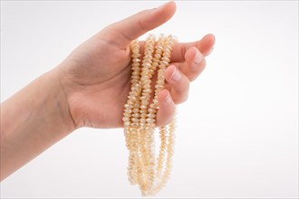 Hand holding pearl necklace on white background