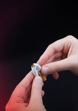 Hand is breaking a cigarette on a black background