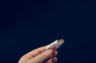 Hand is breaking a cigarette on a black background