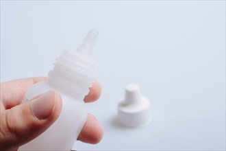 White empty dropper bottle in hand on a white background