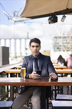 Businessman looking at camera e while holding his smartphone