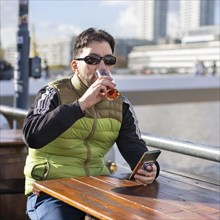 Man drinking a beer while sitting in a bar at the harbor