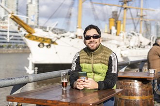 Portrait of a smiling man drinking a beer at the harbor
