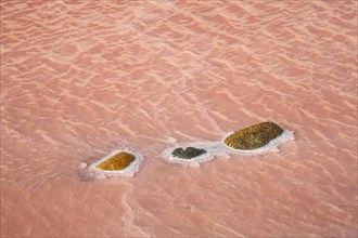 Red salt water with three stones with salt deposit at saline