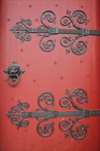 Red church door with fittings and decorations of the Romanesque St Ägidius Abbey Church