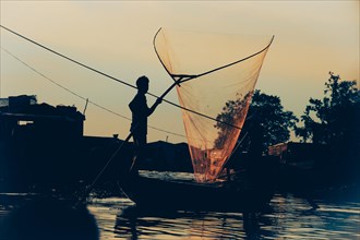 Silhouette of a fisherman with a fish net in the Hau River in Vinh Long
