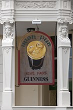 Advertising sign for Guiness beer in front of an Irish pub