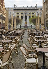 Empty chairs and tables at the Naschmarkt in the early morning with Goethe monument in front of the Old Stock Exchange