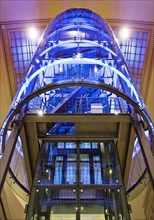 Blue illuminated lift in the cross platform hall seen from bottom to top