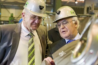 Minister President Winfried Kretschmann with Martin Herrenknecht - both wearing safety helmets - during a visit to Herrenknecht AG