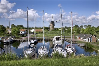 Windmill De Haan and sailing boats in harbour at Brouwershaven