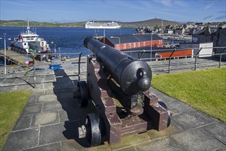 Cannon at 17th century Fort Charlotte in the centre of Lerwick and cruise ship in the Bressay Sound