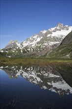 Reflection of mountains of the Mont Blanc massif and the Limestone Pyramids in water of Lago Combal lake in Val Veny in the Italian Alps