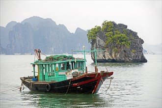 Wooden fishing boat and limestone monolithic islands in Ha Long Bay