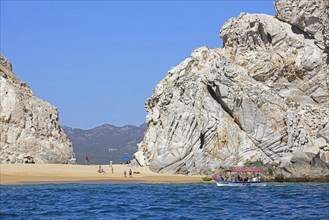 Tourist boat dropping tourists to sunbathe on secluded beach near the seaside resort Cabo San Lucas on the peninsula of Baja California Sur