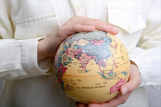 Child holding a small model globe in hand on white background