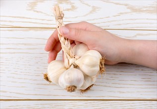 Hand holding cloves of garlic on a wooden texture