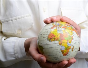 Child holding a small model globe in hand on white background