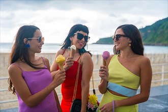 Young female friends on the beach eating ice cream on summer vacation