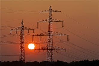 Sunset behind high-voltage pylons